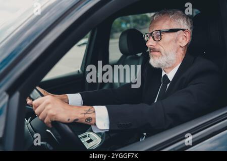 Selbstbewusster, reifer Geschäftsmann, der auf der Straße der Stadt Auto fährt, steht für Reisen und Erfolg Stockfoto