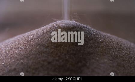 Goldene, glitzernde Sandkörner auf dem Haufen, undichter Sand aus Sanduhr, Makroaufnahme. Zeitverlaufskonzept. Stockfoto