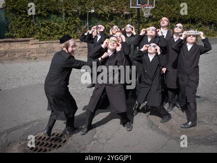 Eine Gruppe von Schülern sieht sich die Sonnenfinsternis von 2024 im Hof ihrer Yeshiva Pfarrschule im Rockland County New York an. Stockfoto