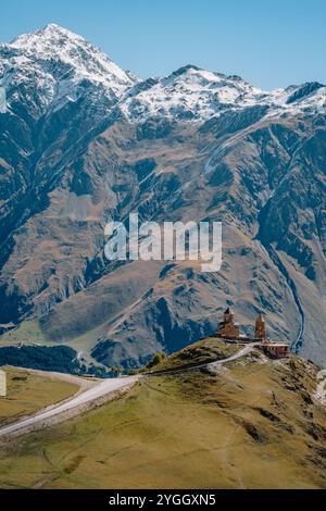 Blick auf die Gergeti Trinity Church in Stepantsminda mit den schneebedeckten Kaukasusbergen im Hintergrund, in Kazbegi, Georgia Stockfoto