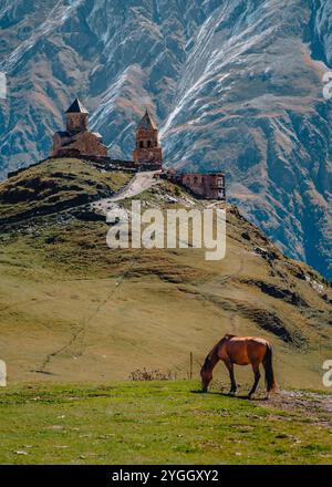 Blick auf die Gergeti Trinity Church in Stepantsminda mit den schneebedeckten Kaukasusbergen im Hintergrund, in Kazbegi, Georgia Stockfoto