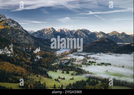 Blick von den Alpen auf die Königsschlösser Neuschwanstein und Hohenschangau mit dem Alpsee und den Allgäuer Alpen in einem herbstlich nebeligen lan Stockfoto