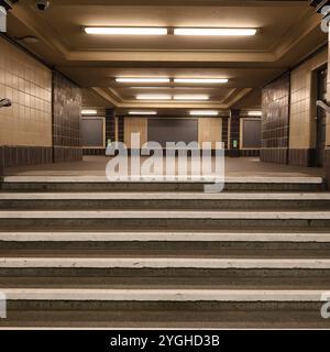 Platz der Luftbrücke. U-Bahn. Berlin. Beigefarbene Fliesen. braune Fliesen. Treppe. Stufen. Symmetrie (Symmetrie). Beleuchtung. Treppen. Schritte. Stufen. Symmetrie. Stockfoto