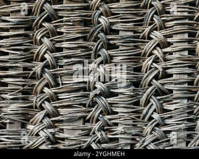 Eine rustikale alte Zaunstruktur aus natürlichen Materialien. Der alte Zaun aus gewebten Zweigen. Stockfoto