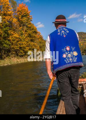 Dunajec, Polen, 10. Oktober 2024: Flößer in traditioneller Kleidung rudern mit Touristen entlang der wunderschönen Dunajec-Schlucht im sonnigen Herbst Stockfoto