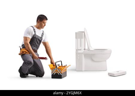 Klempner mit einem Werkzeugkasten, der einen WC-Tank isoliert auf weißem Hintergrund repariert Stockfoto