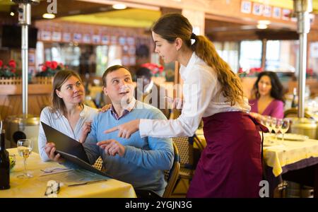 Höfliche junge Kellnerin, die vom Paar im Restaurant bestellt wurde Stockfoto