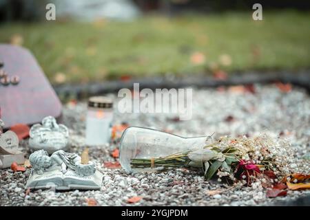 Ein Grab, auf dem eine umgestürzte Vase voller Blumen liegt. Stockfoto