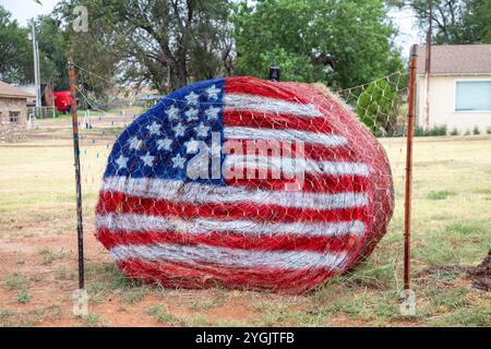 Laverne, Oklahoma – eine amerikanische Flagge ist auf einem Heuballen als Teil einer patriotischen Ausstellung vor einem ländlichen Haus in Oklahoma gemalt. Stockfoto