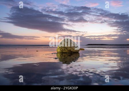 Wasserlandschaft, sanft abfallender Sandstrand mit sanften Wellen. Der nasse Sand reflektiert den unglaublichen Himmel im romantischen Sonnenuntergang in kutan, Bali, Indonesien Stockfoto