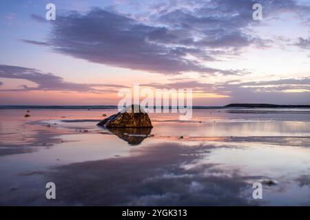 Wasserlandschaft, sanft abfallender Sandstrand mit sanften Wellen. Der nasse Sand reflektiert den unglaublichen Himmel im romantischen Sonnenuntergang in kutan, Bali, Indonesien Stockfoto