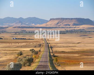 Square Butte, in der Nähe von Fort Shaw, Montana, im Morgenlicht fotografiert. Ein Tal mit Weidevieh, Silos und einer Autobahn sind im Vordergrund. Stockfoto