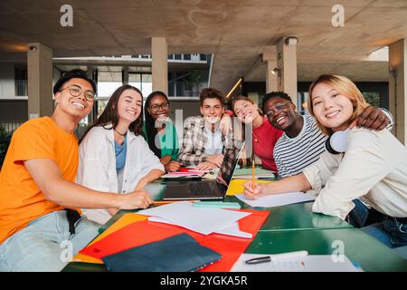 Verschiedene Gruppen von Universitätsstudenten teilen freudige Momente während der Collaborative Study Session, ihr echtes Lächeln und ihre akademische Kameradschaft, während sie gemeinsam an Aufgaben auf dem Campus arbeiten. Hochwertige Fotos Stockfoto