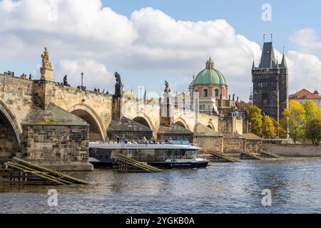 Prag, das Ausflugsboot auf der Moldau führt durch einen Bogen der berühmten mittelalterlichen Karlsbrücke, einer Bogensteinbrücke aus dem Jahr 1357 Stockfoto