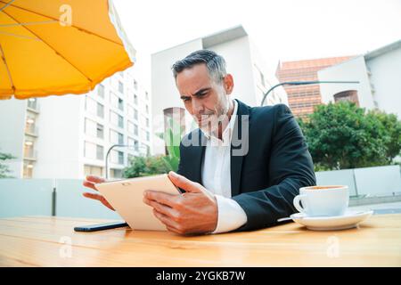 Geschäftsmann mit Tablet in einem Café im Freien erfolgreicher professioneller Manager mittleren Alters, der während der Kaffeepause in der Stadt mit einem digitalen Touchpad arbeitet. Hochwertige Fotos Stockfoto