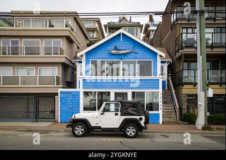 Ein farbenfrohes blaues Haus mit großer Marlin-Fisch-Dekoration auf der Außenseite auf dem Marine Way mit weißem Jeep davor geparkt. Stockfoto