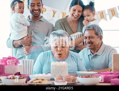 Große Familie, Seniorenpaar und Kerzenblasen mit Party, Kuchen und Liebe zum Geburtstag zu Hause. Mann, Frau und Eltern mit Enkelkindern Stockfoto