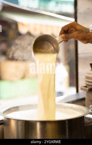 Mann, der kochende Milch ausgießt Stockfoto