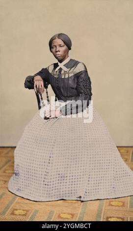 Eine Carte-de-Visite von Harriet Tubman (ca. 46-47) in den Jahren 1868-69. Sie sitzt, nach links gedreht. Eine Hand liegt auf der Rückseite eines Holzstuhls, eine andere auf ihrem Schoß. Erstellt von Benjamin Powelson, 77 Genesee St., Auburn, New York. Harriet Tubman saß in einem Innenraum. Sie ist leicht nach rechts gedreht und blickt von der Kamera ab. Ihre rechte Hand liegt auf der Rückseite eines Holzstuhls und ihre linke Hand auf ihrem Schoß. Ein kühn gemusterter Teppich bedeckt den Boden und die Wand oder fällt hinter ihr in einer leeren hellen Farbe. Tubman trägt ein schwarzes Mieder, das vorne in der Mitte Knöpfe und Stockfoto