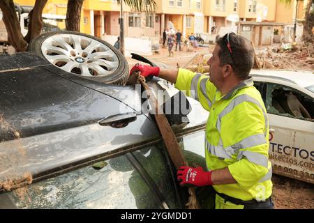 Alfafar, Valencia, Spanien - 7. November 2024. Fachkräfte von EMT Madrid, Empresa Municipal de Transportes de Madrid, Reinigung eines Parks in Alfafar, Valencianische Gemeinde. Sie verwenden LKW und Seile, um die Autos zwischen Baumstamm und Schlamm zu entfernen. Sie bringen sie zu einem nahen leeren Parkplatz, wo sie übereinander gestapelt werden. Stockfoto