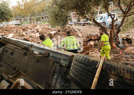 Alfafar, Valencia, Spanien - 7. November 2024. Fachkräfte von EMT Madrid, Empresa Municipal de Transportes de Madrid, Reinigung eines Parks in Alfafar, Valencianische Gemeinde. Sie verwenden LKW und Seile, um die Autos zwischen Baumstamm und Schlamm zu entfernen. Sie bringen sie zu einem nahen leeren Parkplatz, wo sie übereinander gestapelt werden. Stockfoto