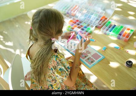 Die Lehrerin in der Werkstatt hat zwei Mädchen beigebracht, wie man ein Thermomosaik zusammenbaut Stockfoto