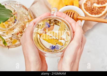 Frau fügt Honig in die Bio-Gebirgsmischung hinzu - Kräuterharmonie - bergige Gelassenheit in Teeritualen. Stockfoto