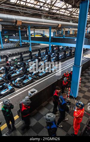 Fahrer, die auf ein Rennen warten, während die Elektro-Gokarts auf der Team Sport Indoor-Kart-Strecke in Warrington, England, aufgeladen werden. Stockfoto