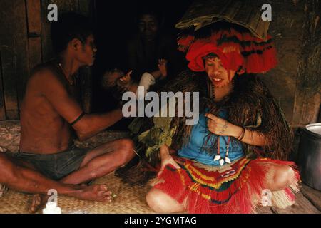 Eingeborene bringen ein Baby aus einer Hütte. Stockfoto