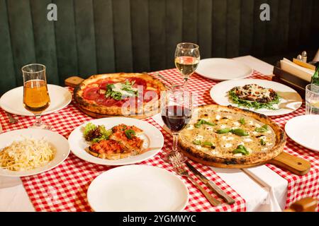 Italienisches Restaurant Tisch mit verschiedenen Pizzen, Pasta-Gerichten und Wein auf karierter Tischdecke Stockfoto