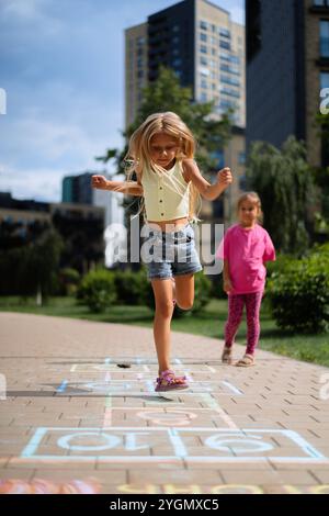 Mädchen, die im Sommer im Hof Hopscotch spielen Stockfoto