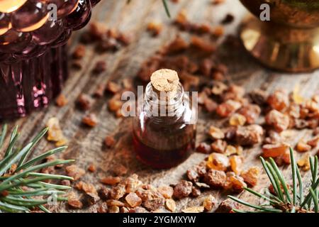 Ätherisches Myrrhenöl in einer Glasflasche mit Fichtenzweigen und Kerze Stockfoto