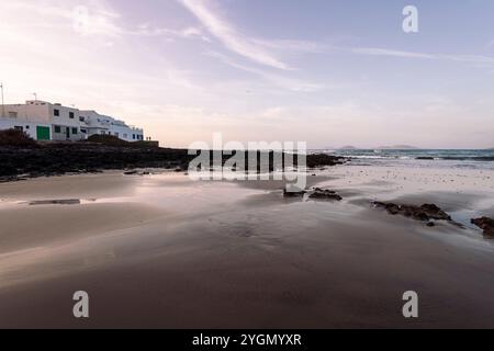 Strand gegen Meer mit Bergen und Haus Stockfoto