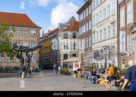 Menschen genießen Essen und Kaffee in einem Café am Gammel Strand Platz mit einer Bronzestuppe von Svend Wiig Hansen auf dem Platz Stockfoto