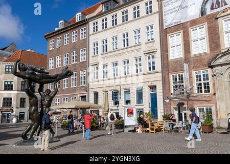 Menschen genießen Essen und Kaffee in einem Café am Gammel Strand Platz mit einer Bronzestuppe von Svend Wiig Hansen auf dem Platz Stockfoto