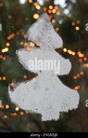 08. November 2024, Brandenburg, Werder (Havel): Ein Weihnachtsbaum auf eine Fensterscheibe gesprüht; im Hintergrund ist eine Lichterkette auf einem Weihnachtsbaum zu sehen. Die diesjährige Weihnachtsbaumsaison wurde in Brandenburg mit dem Fällen der ersten Tannen eröffnet. Foto: Michael Bahlo/dpa Stockfoto