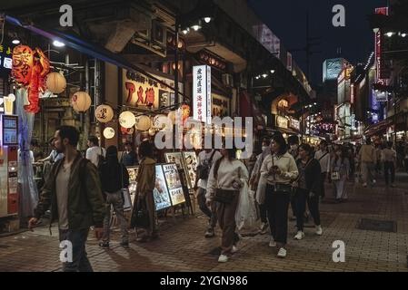 Touristen laufen abends an Restaurants in der Einkaufsstraße Ameyoko im Stadtteil Ueno im Taito-Viertel Tokio vorbei Stockfoto