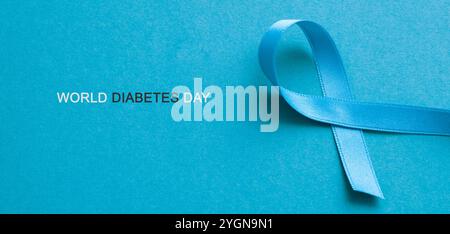 Ein blaues Awareness-Band und der Text World Diabetes Day auf blauem Hintergrund Stockfoto