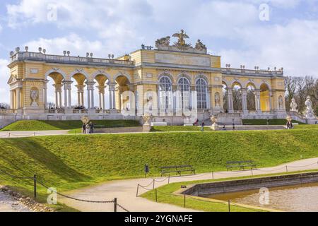 Wien, Österreich, 3. April 2015: Die Gloriette im Schlosspark Schönbrunn vor dem wolkenblauen Himmel. Touristen, die herumlaufen, Europa Stockfoto