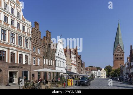 Historische umliegende Giebelhäuser mit vielen Geschäften und Restaurants auf dem Platz am Sande in der mittelalterlichen Altstadt von Lüneburg und St. Johannis Churc Stockfoto