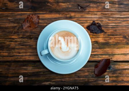 Eine Tasse Kaffee auf Holztisch und braune Herbstblätter. Draufsicht, flach. Stockfoto