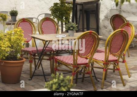 Draußen leerer Kaffee und Restaurantterrasse mit roten und weißen Stühlen und Tisch, Blumen Stockfoto