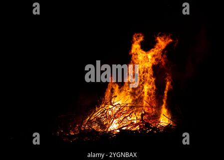 Großes Lagerfeuer mit Flammen, die nachts in der Luft schossen. Das Feuer hat die Farben Rot, Orange und Gelb. Da fliegen Funken in der Luft Stockfoto