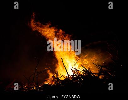 Großes Lagerfeuer mit Flammen, die nachts in der Luft schossen. Das Feuer hat die Farben Rot, Orange und Gelb. Da fliegen Funken in der Luft Stockfoto