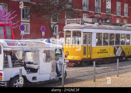 Lissabon, Portugal, 27. März 2018: Gelbe Straßenbahn, Symbol von Lissabon an der farbenfrohen Downtown Street und Frühlingsblütenbaum, Europa Stockfoto