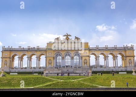 Wien, Österreich, 3. April 2015: Die Gloriette im Schlosspark Schönbrunn vor dem wolkenblauen Himmel. Touristen, die herumlaufen, Europa Stockfoto