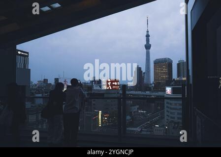 Zwei Besucher fotografieren am Abend den 634 Meter hohen Tokyo Skytree auf der Aussichtsplattform des Asakusa Cultural Center Stockfoto