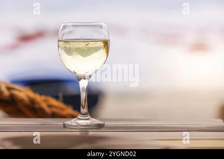 Weißer Wein auf dem Holztisch, Küstencafé, Hintergrund Austernfarm Stockfoto