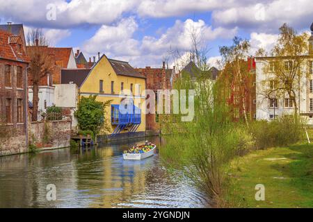 Gent, Belgien, 12. April 2016: Alte Häuser entlang des Kanals und Boot mit Touristen im beliebten Touristenziel Gent, Europa Stockfoto