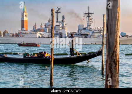 Gondoliere fährt Gondelfahrt auf dem canale von Venedig mit einem Schlachtschiff im Hintergrund Stockfoto